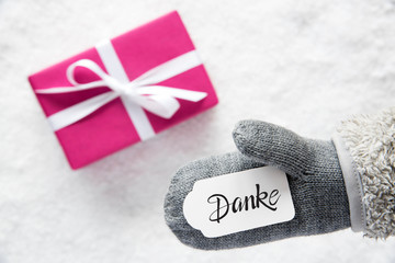 Label With German Calligraphy Danke Means Thank You. Gray Glove With Pink Gift And Snow Background