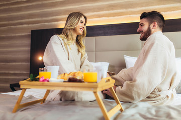 Young happy couple having breakfast in luxury hotel room