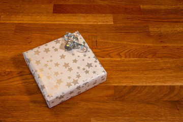 Fond de bois chaud avec un paquet cadeau carré et ruban brillant avec étoiles dorées