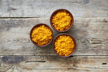 Turmeric powder in small bowls on wooden background