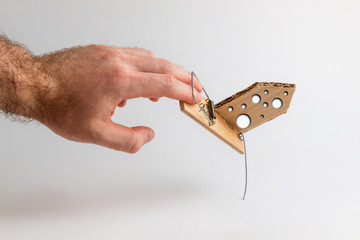Bank investments and risks. A man's hand caught in a mousetrap with a schematic cardboard house,...