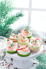 Assorted canapes with shrimps - with fresh cucumbers, cherry tomatoes, bread, crackers at the festive Christmas table, selective focus