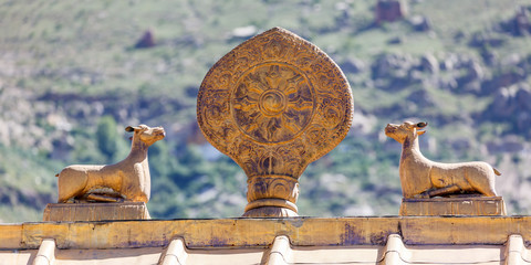 LHASA, TIBET / CHINA - July 31, 2017: Golden colored dharma wheel and deers on the roof top of Sera...