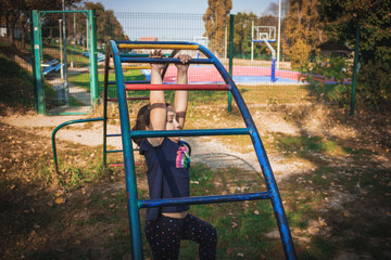 Small girl hanging on monkey bars on the playground.