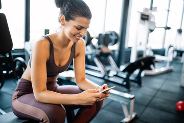 Portrait of sport woman using mobile after exercise at gym.