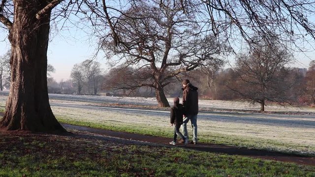 Father And Son Walking In English Park On Bright Winter day