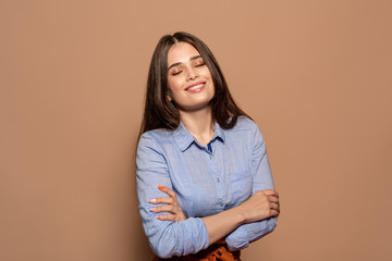 Freestyle. Young girl standing studio isolated on brown crossed arms closed eyes delightful