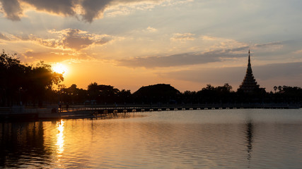 Naklejka premium The setting sun is setting at a lake near a Buddhist temple in Asia.