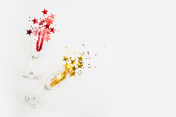 Confetti in the form of stars poured glasses of champagne on a white background. View from above.