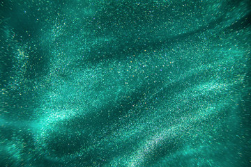 Fototapeta na wymiar Abstract elegant, detailed mint glitter particles flow with shallow depth of field underwater. Holiday magic shimmering luxury background. Festive sparkles and lights. de-focused