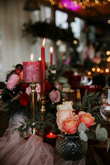 Obraz na płótnie Canvas Beautiful, decorated table with flower decorations and red candles. Christmas evening or wedding party decoration.