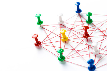 Network with colorful pins and string,  linked together with string on a white background suggesting a network of connections.