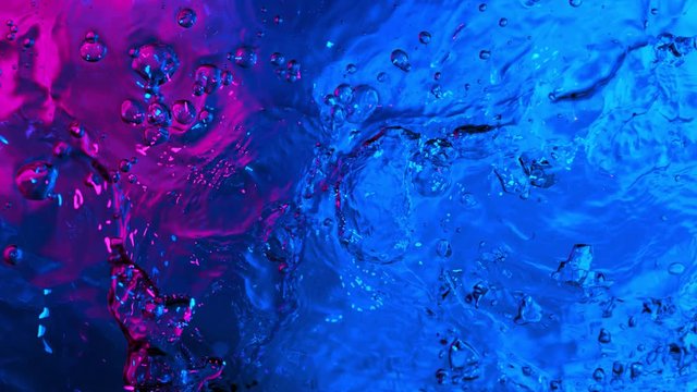 Super slow motion of splashing water illuminated by neon lights. Filmed on very high speed camera, 1000 fps.