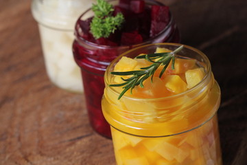 Pickled red, white, orange beet in glass jars. Variety pickles on rustic background