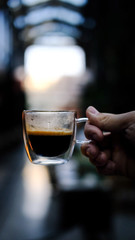 Transparent glass cup of coffee in the hand. Coffee in a cafe. 