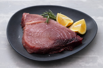 raw tuna with salt and lemon on dark plate