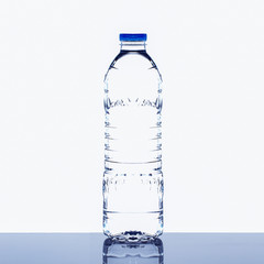 Mineral drinking water bottle on glossy table on white background