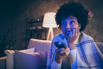 Close up photo of terrified afro american girl sit divan watch horror film hold remote control...