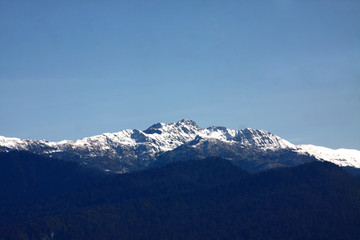 Fototapeta na wymiar View over snow-covered mountain peak against blue sky