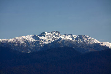 Fototapeta na wymiar View over snow-covered mountain peak against blue sky