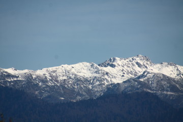 View over snow-covered mountain peak against blue sky