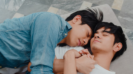 Young Asian gay couple sleep together at home. Teen korean LGBTQ+ men happy relax rest lying on bed in bedroom at house in the morning. - obrazy, fototapety, plakaty