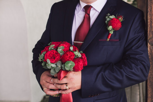 Red roses wedding bouquet in hands of the grrom
