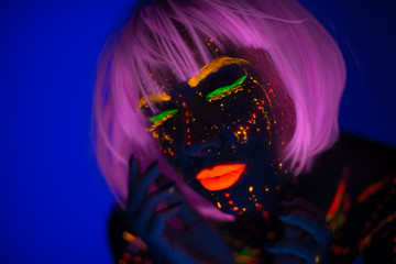 Portrait of Beautiful Fashion Woman in Neon UF Light. Model Girl with Fluorescent Creative Psychedelic MakeUp, Art Design of Female Disco Dancer Model in UV, Colorful Abstract Make-Up. Dancing Lady