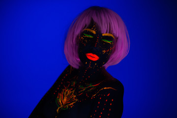 Portrait of Beautiful Fashion Woman in Neon UF Light. Model Girl with Fluorescent Creative Psychedelic MakeUp, Art Design of Female Disco Dancer Model in UV, Colorful Abstract Make-Up. Dancing Lady