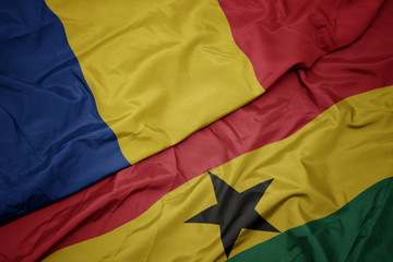 waving colorful flag of ghana and national flag of romania.
