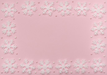 Fototapeta na wymiar Christmas pink background with white snowflakes and beads. New Year greeting card. Flat lay style. 