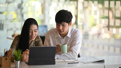 Two colleagues working with tablet in modern office.