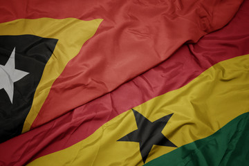 waving colorful flag of ghana and national flag of east timor.