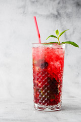 Glass with strawberry mojito cocktail with lemon and mint, cold refreshing drink or beverage with ice on bright marble background. Overhead view, copy space. Advertising for cafe menu. Vertical photo.