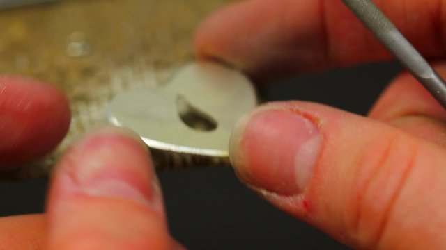 Macro of a goldsmith cutting and filing the steel to make a ring. Concept: silver, style, production