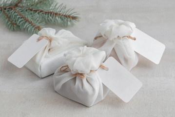 Christmas present wrapped with white furoshiki fabric with labels. Eco friendly gift.