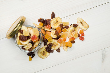 top view of glass jar with dried fruits scattered on wooden table