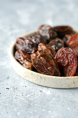 Dried dates and plums on a gray background