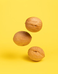 Delicious flying walnuts on bright yellow background.