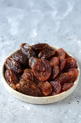 Dried dates and plums on a gray background