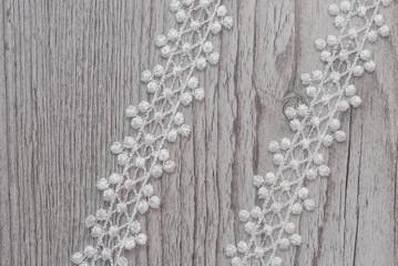 White wooden background with white spring flowers roses and lace ribbon. Happy womans day. The texture of lace on wooden background.