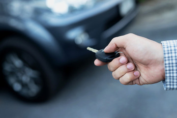 Car key in business man hand.  hand presses on the remote control car alarm systems. lock or unlock the door.