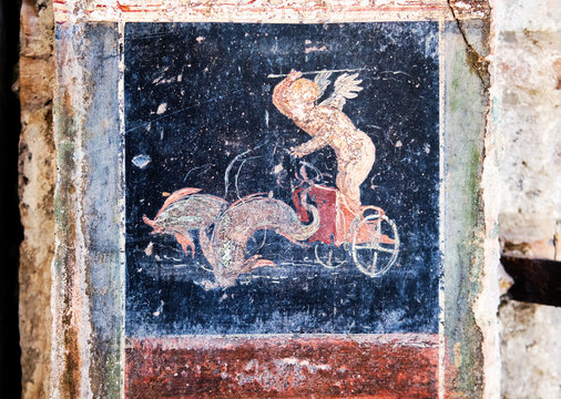 Winged Amorino leads a fish-drawn chariot, a figure of divinity of ancient Rome in Pompeii.