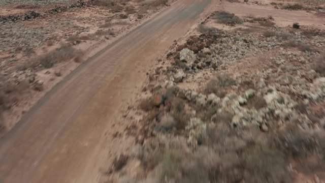 Fast flying dirt road aerial view with sand and stones