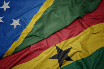 waving colorful flag of ghana and national flag of Solomon Islands .