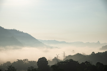 yellow bright multi layer mountain and high voltage power line in morning view with mist