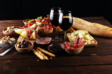 Italian antipasti wine snacks set. Cheese variety, Mediterranean olives, seafood salad, Prosciutto di Parma, tomatoes, anchovy and wine in glasses