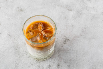 Glass with cold brew coffee and milk isolated on bright marble background. Overhead view, copy space. Advertising for cafe menu. Coffee shop menu. Horizontal photo.