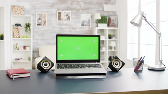 Modern laptop with green screen lying on the table