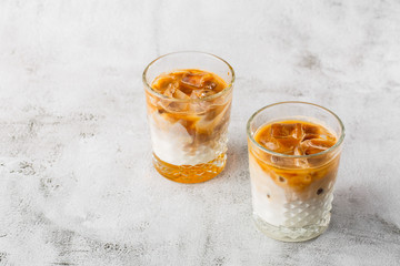 Two glasses with cold brew coffee and milk isolated on bright marble background. Overhead view, copy space. Advertising for cafe menu. Coffee shop menu. Horizontal photo.